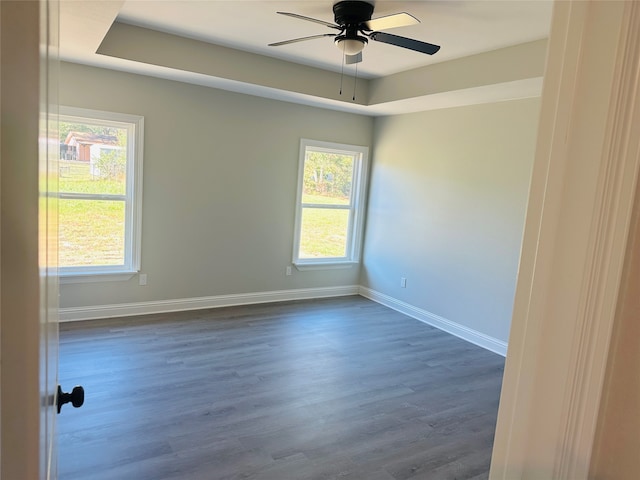 empty room featuring dark wood-type flooring, ceiling fan, and plenty of natural light