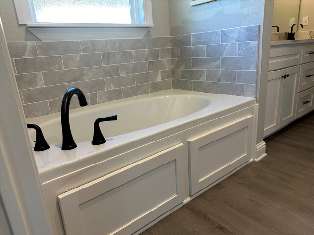 bathroom with vanity, hardwood / wood-style floors, and a tub to relax in