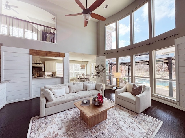 living area featuring dark wood-type flooring, visible vents, and ceiling fan