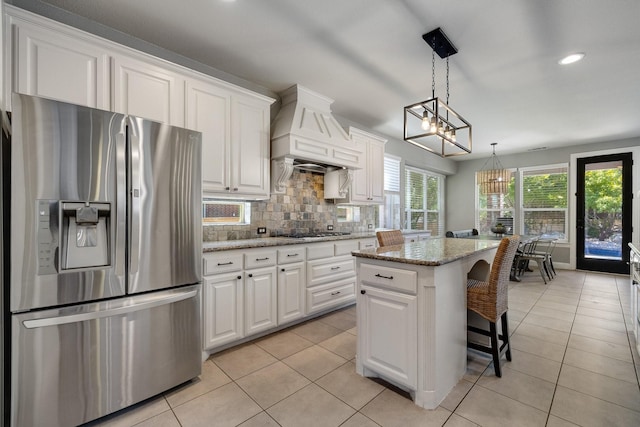 kitchen with light tile patterned flooring, premium range hood, gas stovetop, stainless steel fridge with ice dispenser, and tasteful backsplash