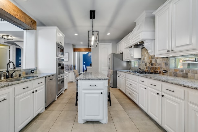 kitchen with sink, stainless steel appliances, a center island, light stone countertops, and white cabinets