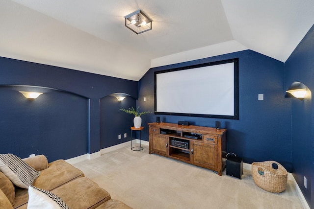 carpeted cinema room featuring vaulted ceiling and baseboards