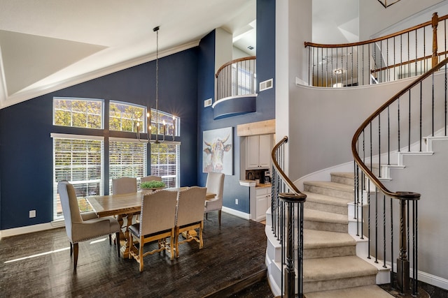 dining area featuring a towering ceiling, dark wood-type flooring, and a notable chandelier