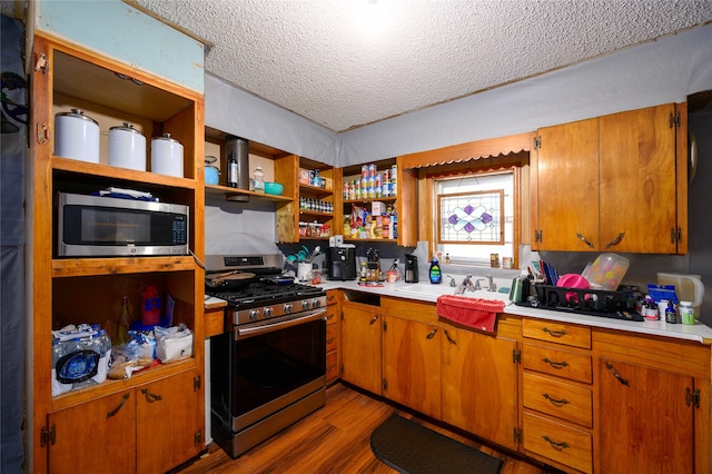 kitchen featuring light hardwood / wood-style floors, a textured ceiling, sink, and appliances with stainless steel finishes