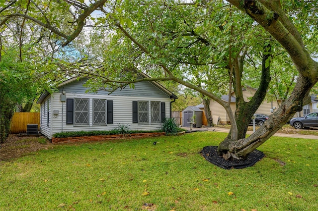 view of front of house with central AC unit, a shed, and a front yard