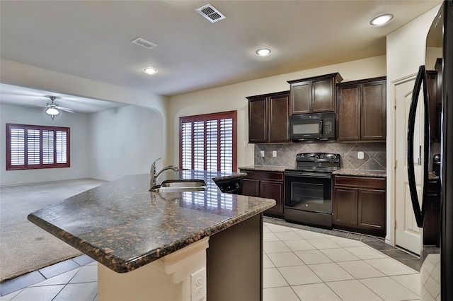 kitchen featuring light tile patterned flooring, sink, black appliances, ceiling fan, and a kitchen island with sink