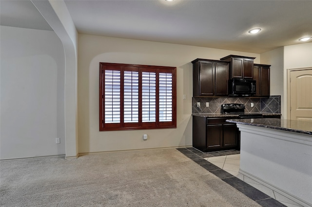 kitchen with dark brown cabinetry, black appliances, light carpet, and dark stone counters