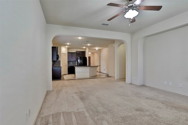 unfurnished living room featuring light colored carpet and ceiling fan