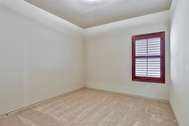 empty room with light colored carpet and a textured ceiling