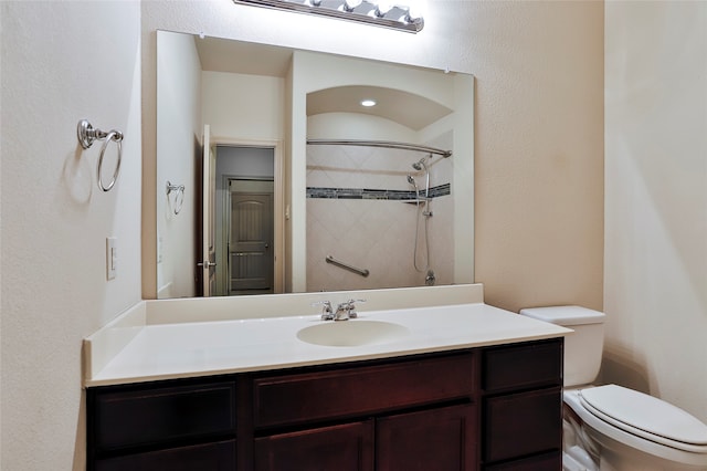 bathroom with tiled shower, vanity, and toilet