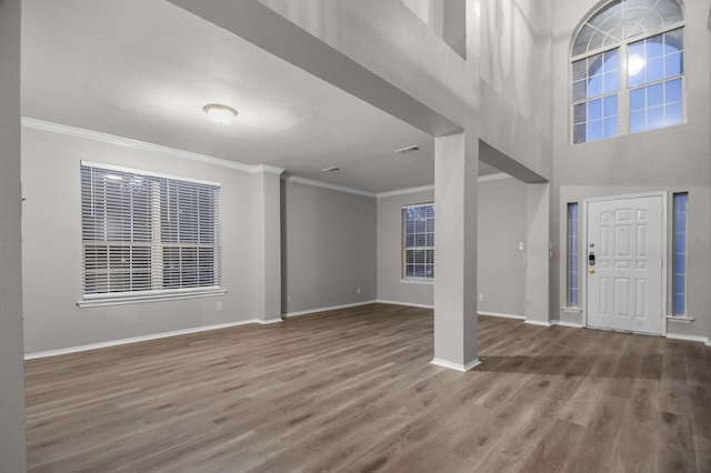 entryway with a high ceiling, wood-type flooring, and crown molding