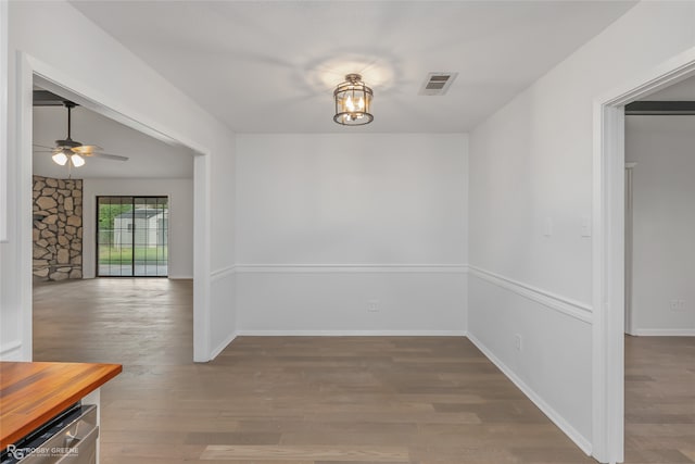 unfurnished dining area featuring wood-type flooring and ceiling fan with notable chandelier