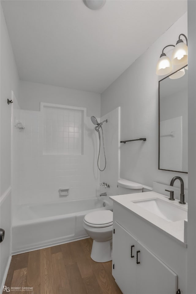 full bathroom featuring wood-type flooring, tiled shower / bath combo, toilet, and vanity