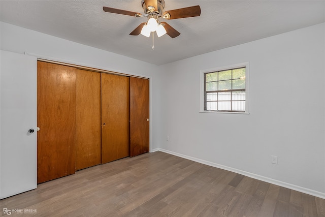 unfurnished bedroom featuring a textured ceiling, light wood-type flooring, ceiling fan, and a closet