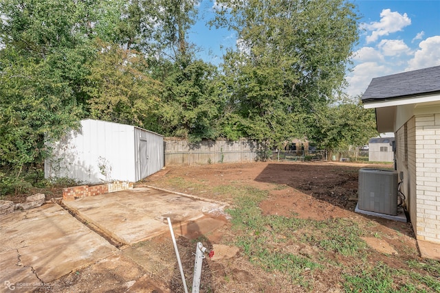 view of yard with central AC unit, a shed, and a patio area