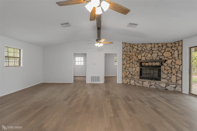 unfurnished living room featuring hardwood / wood-style flooring, a healthy amount of sunlight, and a stone fireplace