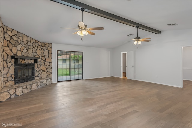 unfurnished living room with light wood-type flooring, a stone fireplace, vaulted ceiling with beams, and ceiling fan