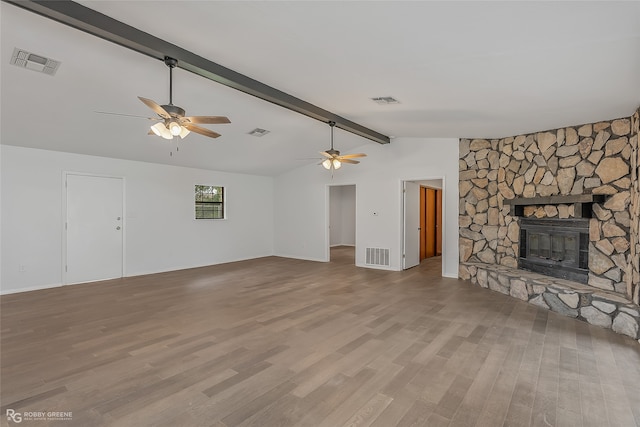 unfurnished living room with a stone fireplace, light wood-type flooring, vaulted ceiling with beams, and ceiling fan