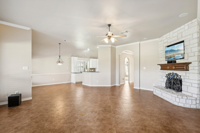 unfurnished living room featuring a stone fireplace, ceiling fan, and ornamental molding