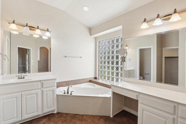 bathroom featuring tile patterned floors, vaulted ceiling, toilet, a bathtub, and vanity