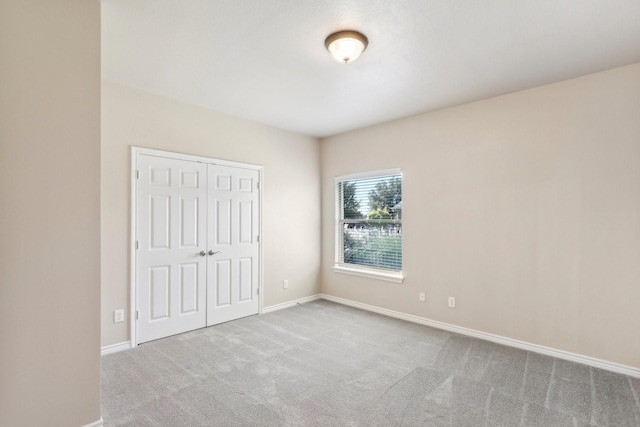 unfurnished bedroom with light colored carpet and a closet