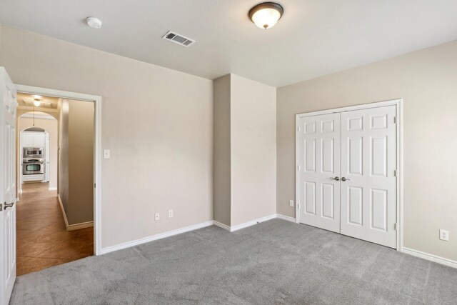 unfurnished bedroom featuring light colored carpet and a closet