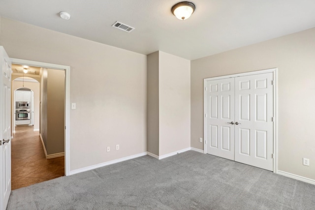 unfurnished bedroom with light colored carpet and a closet