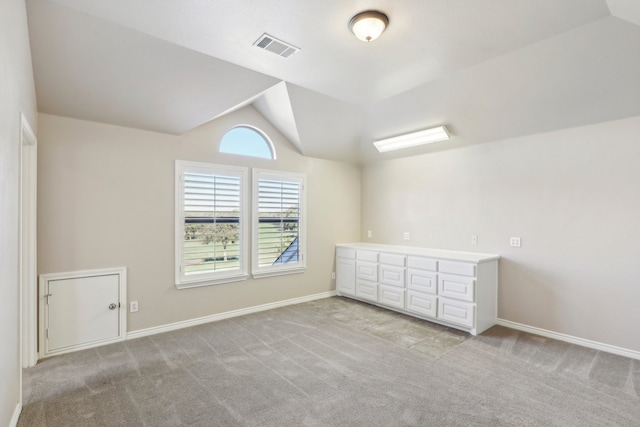 empty room featuring light colored carpet and lofted ceiling