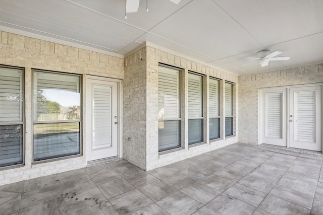 view of exterior entry featuring ceiling fan and a patio