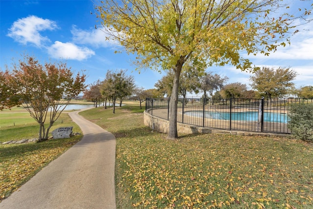 view of home's community with a pool, a lawn, and a water view