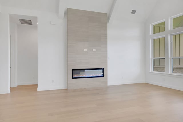 unfurnished living room with a tile fireplace, light hardwood / wood-style floors, and high vaulted ceiling