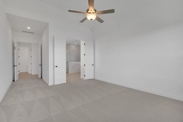 unfurnished bedroom featuring connected bathroom, light carpet, and ceiling fan