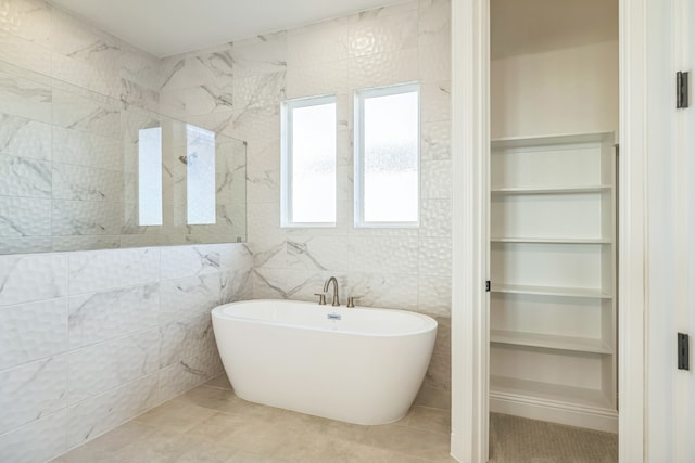 bathroom with a bathing tub, tile patterned flooring, and tile walls