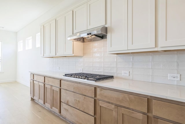 kitchen with light hardwood / wood-style floors, stainless steel gas cooktop, and backsplash