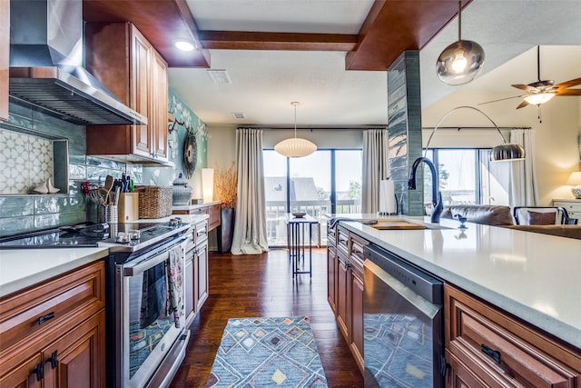 kitchen featuring appliances with stainless steel finishes, tasteful backsplash, dark wood-type flooring, sink, and wall chimney range hood