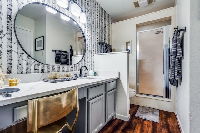 bathroom featuring hardwood / wood-style floors, vanity, an enclosed shower, and toilet