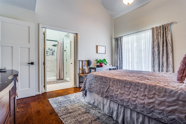 bedroom featuring ensuite bath, dark wood-type flooring, and lofted ceiling