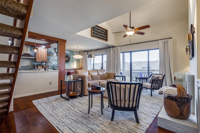 living room featuring vaulted ceiling with skylight, ceiling fan, and dark wood-type flooring