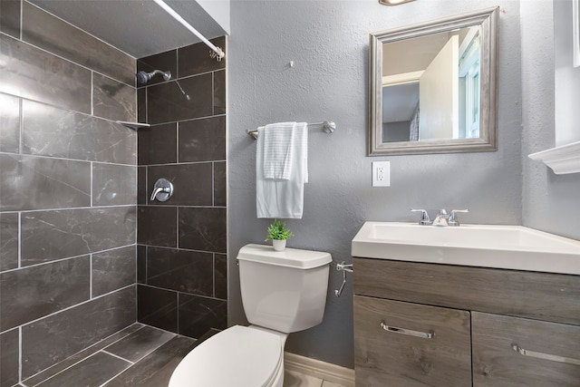 bathroom with vanity, toilet, and a tile shower