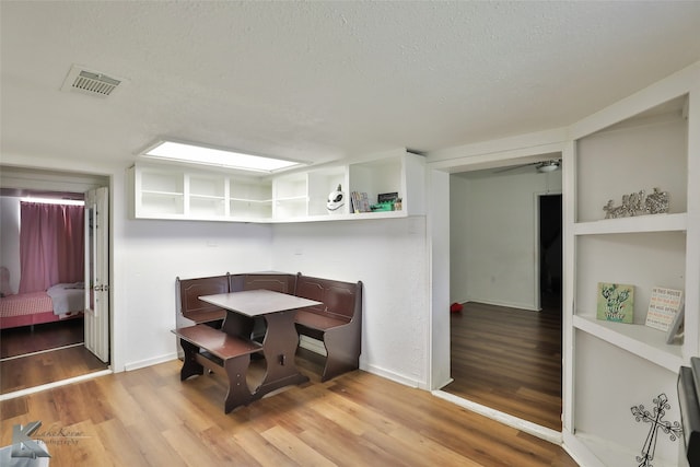 dining room with light wood-type flooring and a textured ceiling