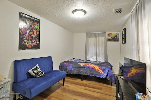 bedroom with a textured ceiling and wood-type flooring