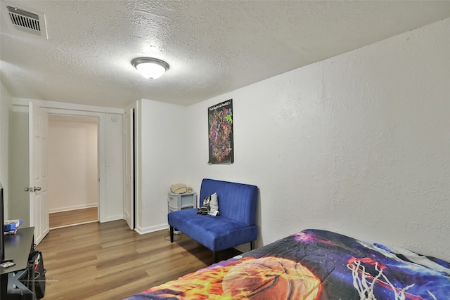 bedroom with a textured ceiling and hardwood / wood-style flooring