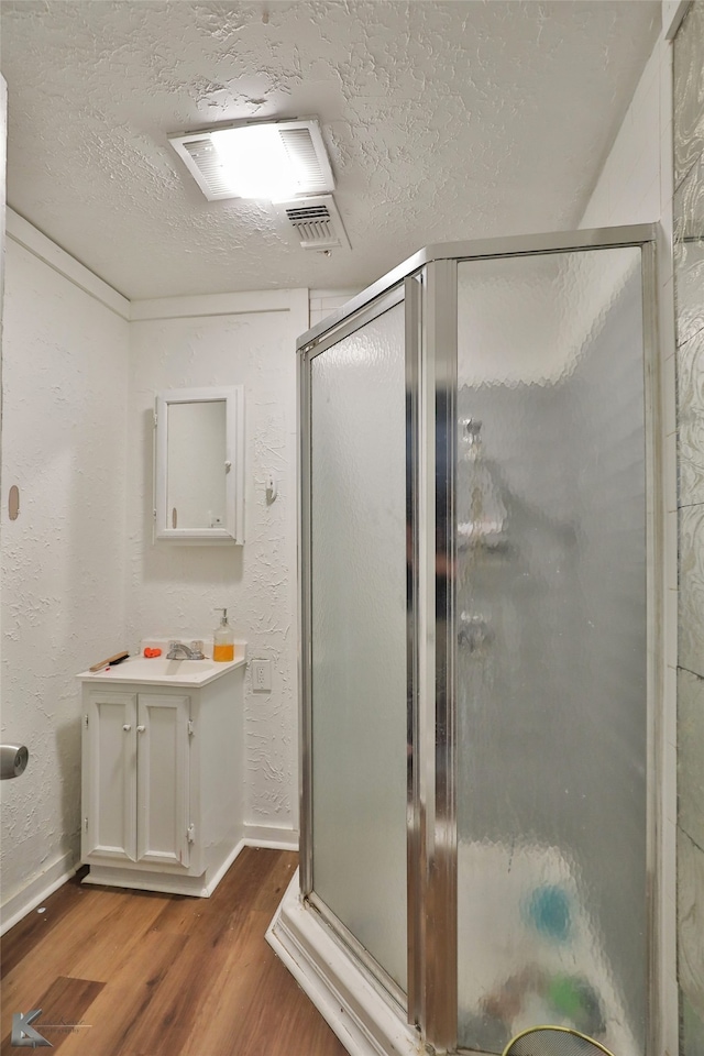 bathroom featuring walk in shower, vanity, a textured ceiling, and hardwood / wood-style flooring