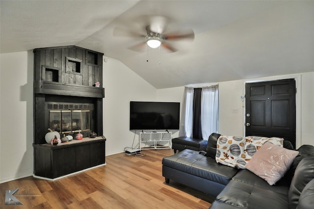 living room with a large fireplace, vaulted ceiling, ceiling fan, and wood-type flooring