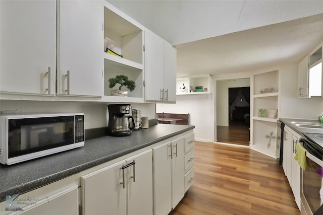 kitchen with white cabinetry, sink, stainless steel range, light hardwood / wood-style floors, and dishwashing machine