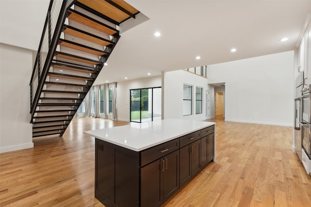 kitchen featuring a center island, white cabinets, dark brown cabinetry, and light hardwood / wood-style flooring