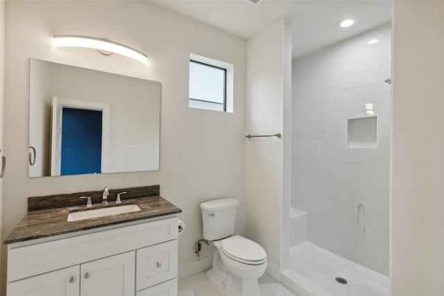 bathroom featuring tiled shower, toilet, and vanity