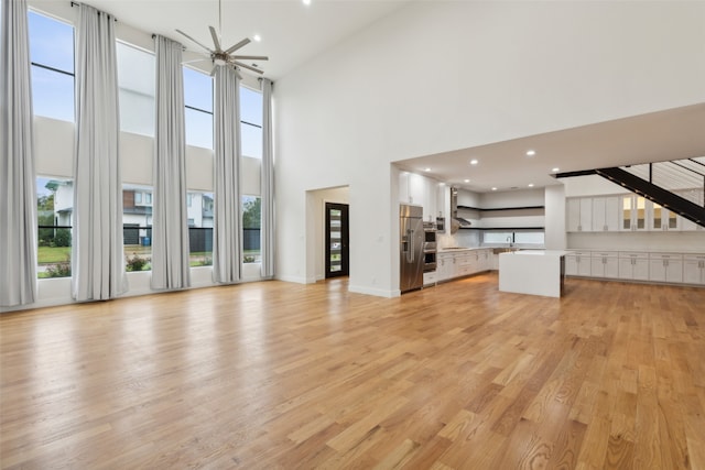 unfurnished living room with a high ceiling, a wealth of natural light, and light hardwood / wood-style flooring