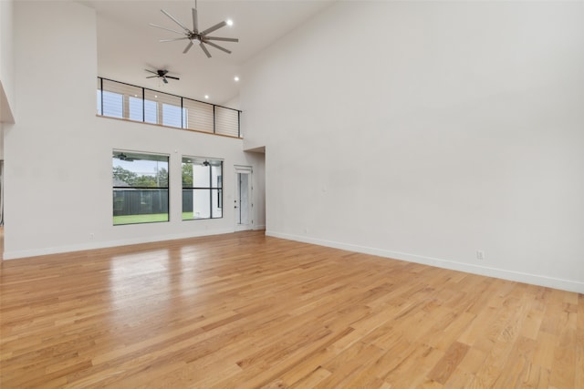 unfurnished living room with high vaulted ceiling, light wood-type flooring, and ceiling fan