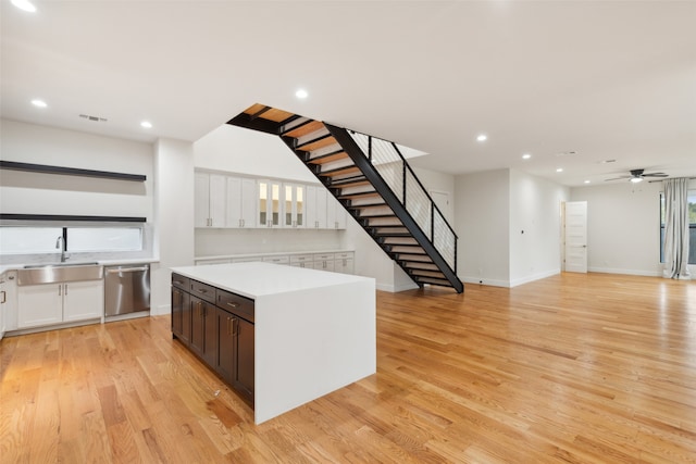 kitchen with sink, a center island, white cabinets, light wood-type flooring, and dishwasher